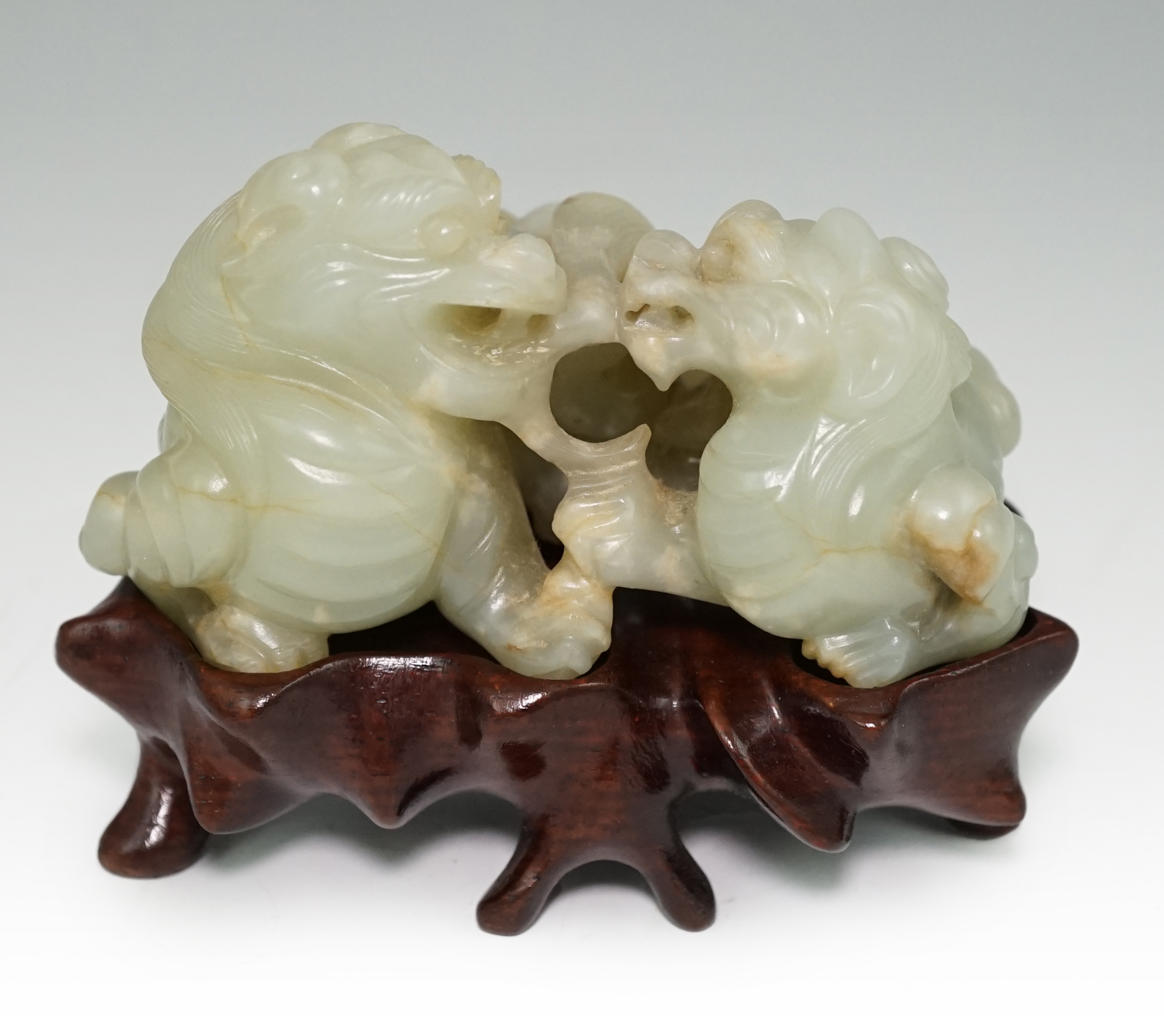 A Chinese celadon and russet jade group of two lion-dogs, 19th century